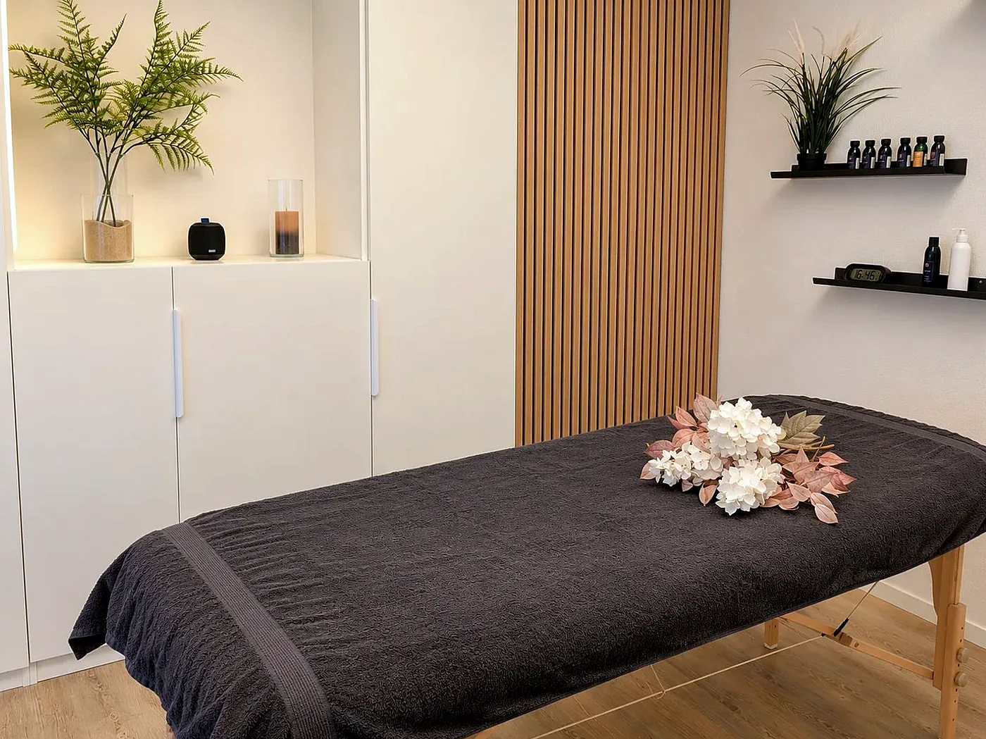 Ruhiger Behandlungsraum mit Liege und Holzwand