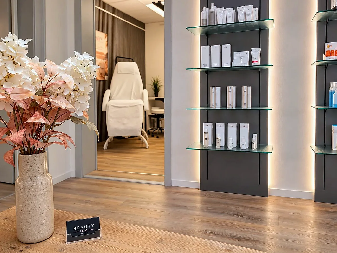 Empfang von beautyinc mit beleuchteten Produktregalen und Blick in den Behandlungsraum